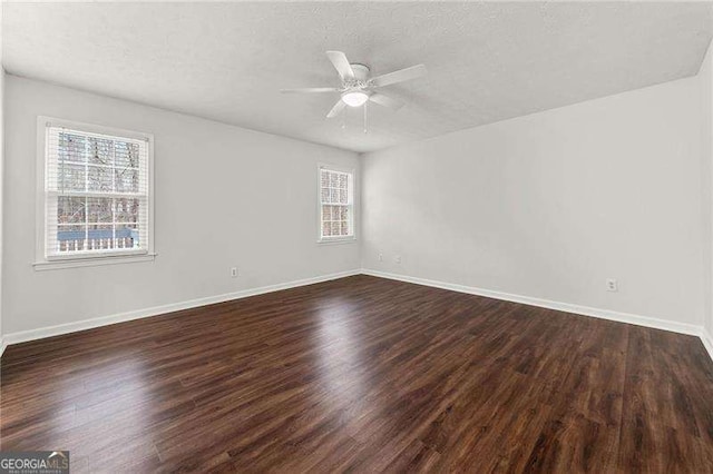 spare room featuring a ceiling fan, a textured ceiling, baseboards, and dark wood-style flooring