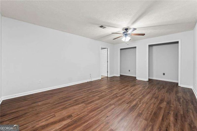 unfurnished bedroom featuring visible vents, dark wood finished floors, a textured ceiling, and baseboards