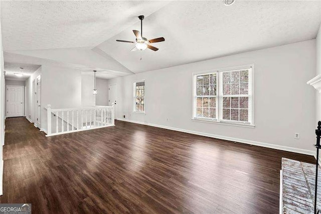 unfurnished living room with lofted ceiling, a textured ceiling, baseboards, and wood finished floors