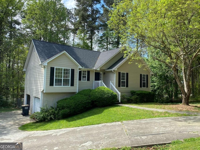 view of front of house featuring a garage, concrete driveway, roof with shingles, and a front yard