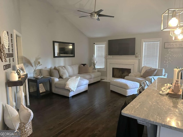 living area with ceiling fan, a fireplace, high vaulted ceiling, and dark wood-style flooring