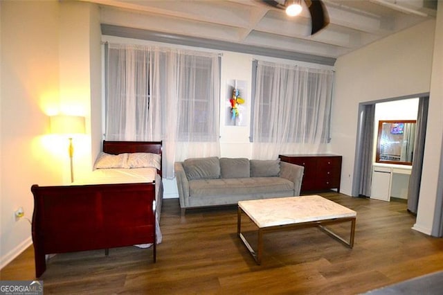 living room featuring beam ceiling, baseboards, and wood finished floors