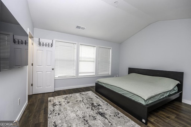 bedroom with vaulted ceiling, wood finished floors, visible vents, and baseboards