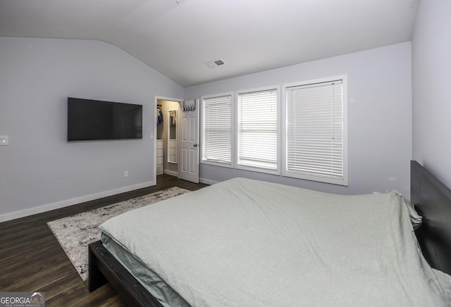 bedroom with baseboards, visible vents, dark wood finished floors, a spacious closet, and vaulted ceiling