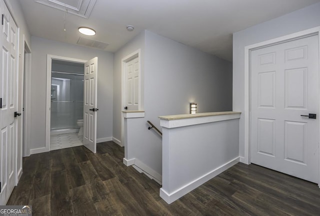 hallway featuring dark wood-style floors, baseboards, an upstairs landing, and attic access