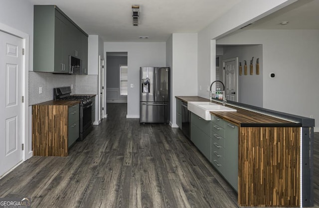 kitchen featuring dark wood-style floors, stainless steel appliances, butcher block counters, a sink, and a peninsula