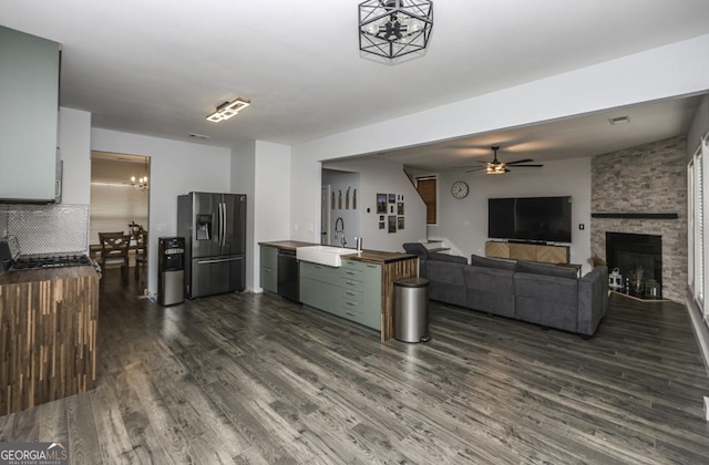 kitchen with black dishwasher, dark wood finished floors, stainless steel refrigerator with ice dispenser, a sink, and butcher block countertops