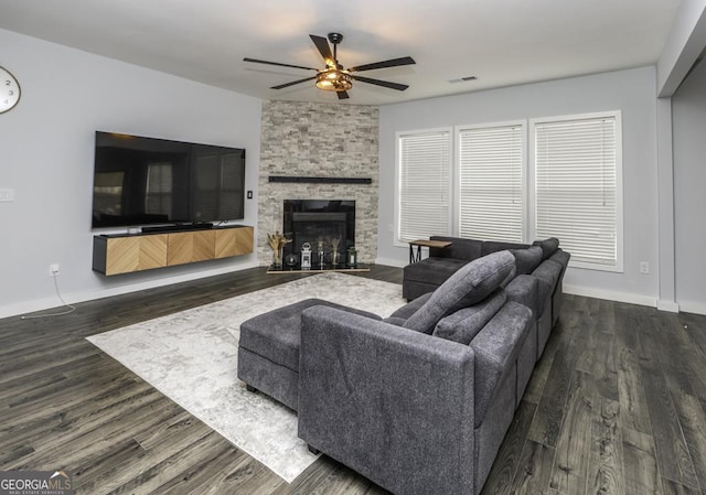 living area featuring a ceiling fan, a fireplace, baseboards, and wood finished floors