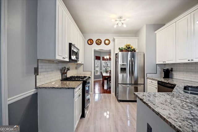 kitchen featuring light stone countertops, appliances with stainless steel finishes, a chandelier, and white cabinets