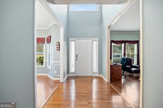 foyer with crown molding, baseboards, and hardwood / wood-style floors