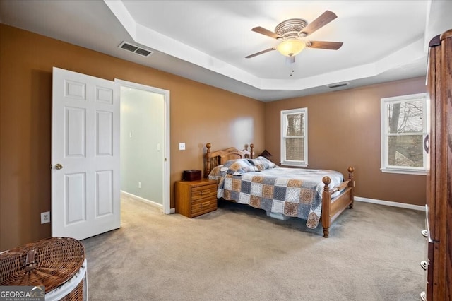 carpeted bedroom with a tray ceiling, baseboards, and visible vents