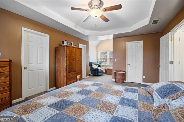 bedroom featuring visible vents, ceiling fan, baseboards, and a tray ceiling