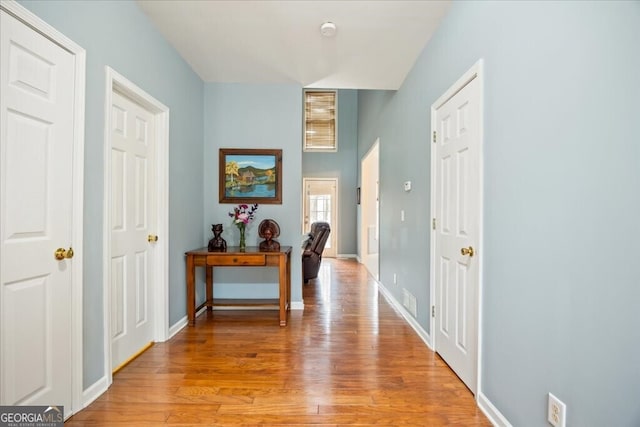 hall featuring light wood finished floors, visible vents, and baseboards