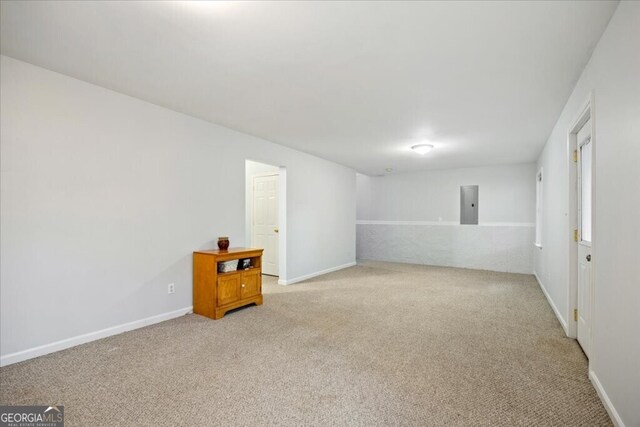 spare room with electric panel, baseboards, and light colored carpet