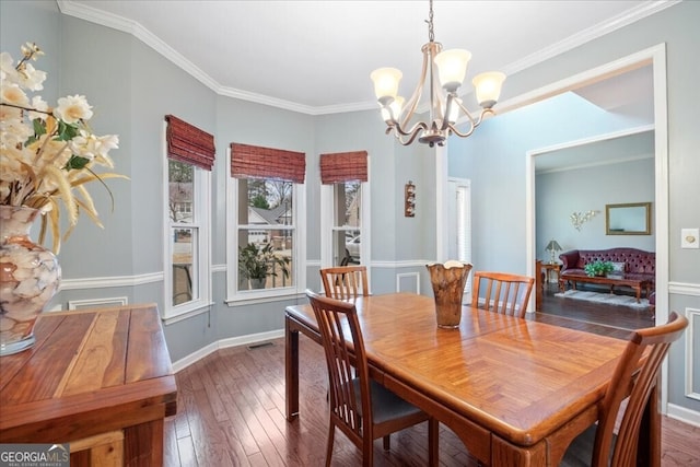 dining room with crown molding, an inviting chandelier, and hardwood / wood-style flooring