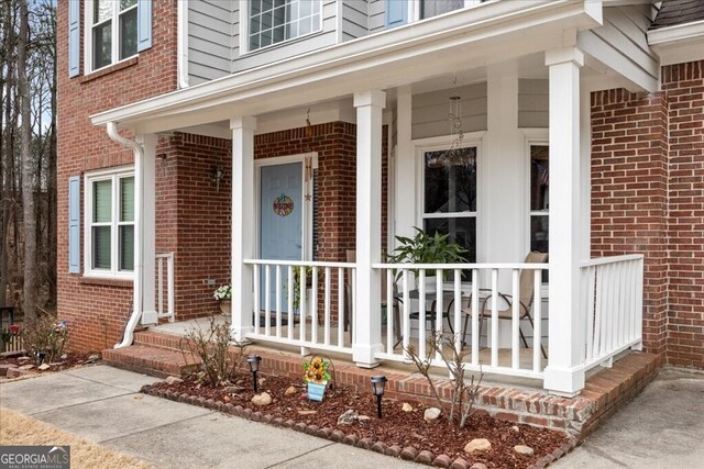 view of exterior entry featuring brick siding and a porch