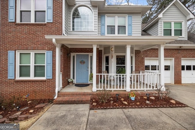 view of front of home with concrete driveway, brick siding, and covered porch