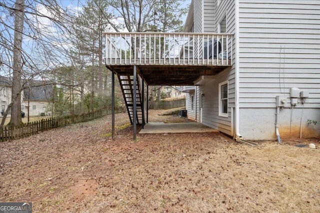 view of yard featuring a carport, a wooden deck, stairs, and fence