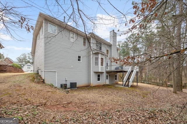 rear view of house featuring a chimney, a deck, and stairs