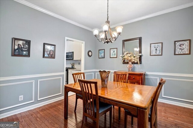 dining room featuring wainscoting, ornamental molding, an inviting chandelier, and wood-type flooring