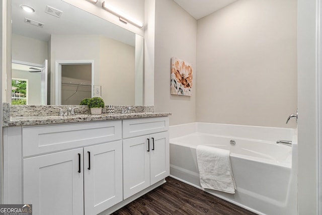 full bathroom featuring a bath, visible vents, wood finished floors, and vanity