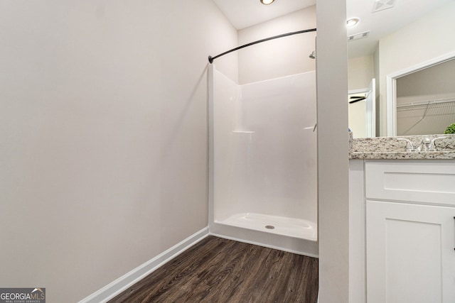 bathroom with a walk in shower, wood finished floors, vanity, and baseboards