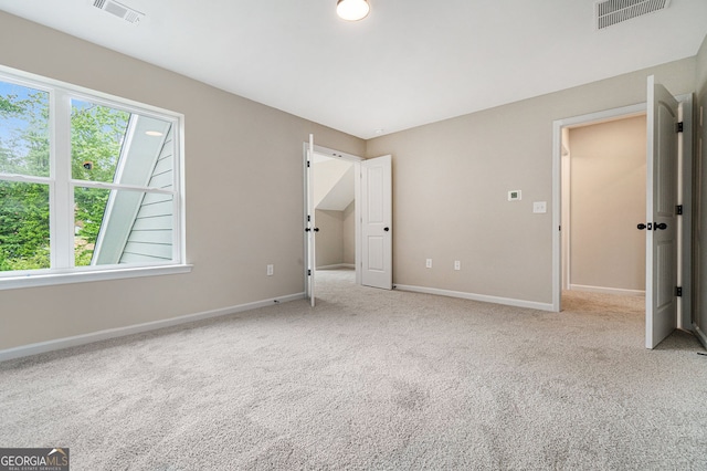 unfurnished bedroom featuring multiple windows, visible vents, and carpet flooring