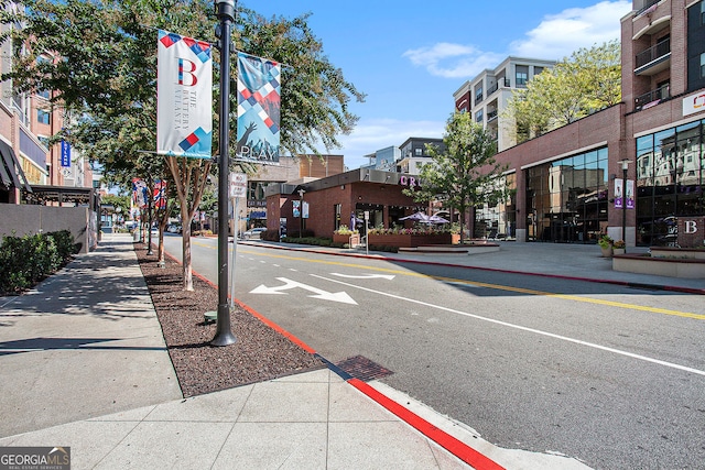 view of road with sidewalks, street lights, and curbs