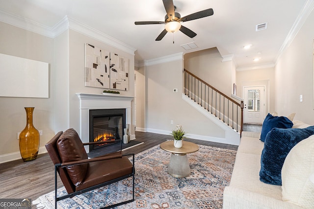 living area with a glass covered fireplace, visible vents, stairway, and wood finished floors