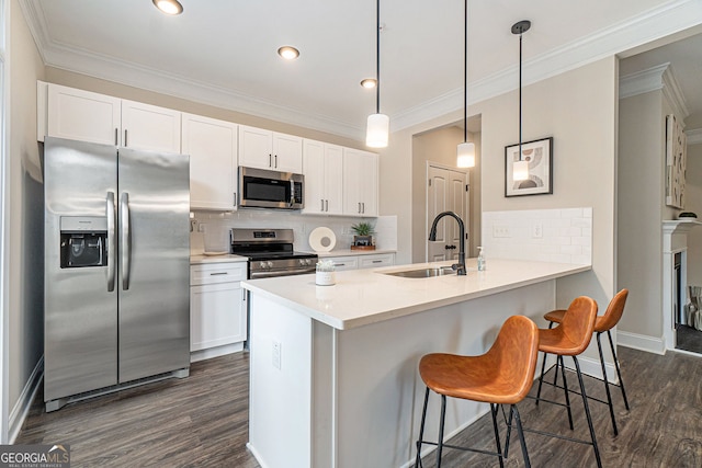 kitchen featuring dark wood finished floors, stainless steel appliances, ornamental molding, a sink, and a kitchen breakfast bar