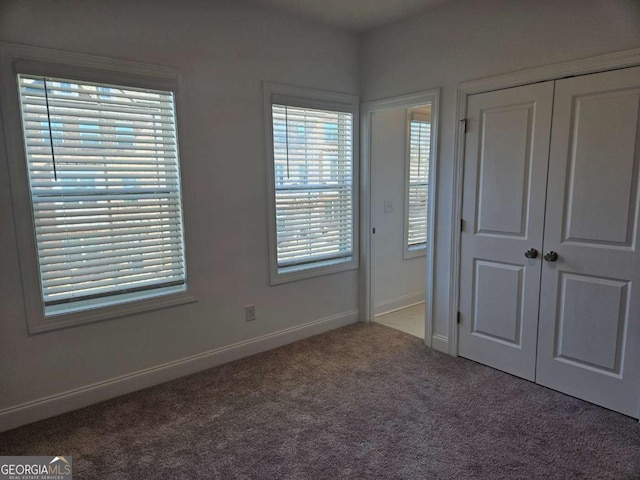 unfurnished bedroom featuring carpet, baseboards, and a closet