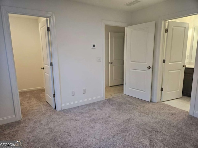 unfurnished bedroom featuring light carpet, visible vents, and baseboards