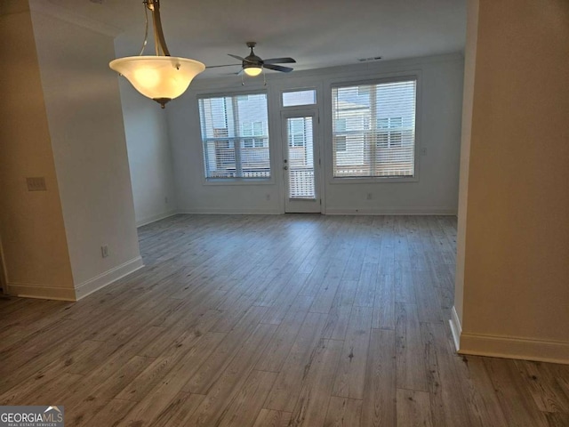 unfurnished living room featuring a ceiling fan, visible vents, baseboards, and wood finished floors