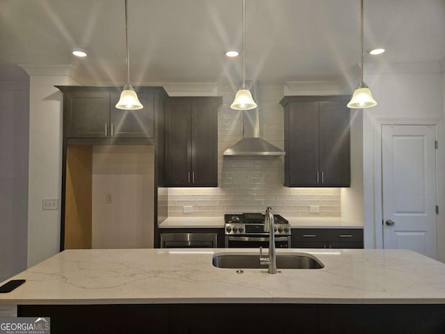 kitchen with decorative backsplash, a sink, an island with sink, light stone countertops, and stainless steel gas range oven