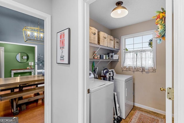 laundry room with baseboards, an inviting chandelier, laundry area, a textured ceiling, and washing machine and dryer