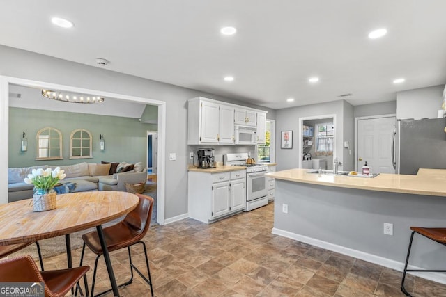 kitchen with light countertops, recessed lighting, white appliances, white cabinetry, and a sink