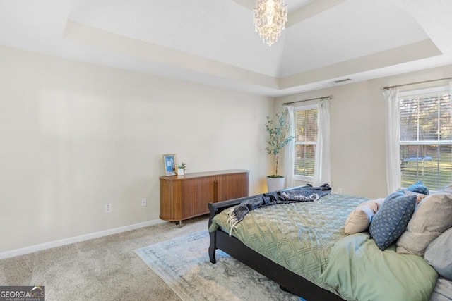 bedroom featuring a raised ceiling, multiple windows, and visible vents