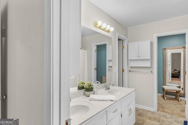 full bathroom featuring double vanity, baseboards, and a sink