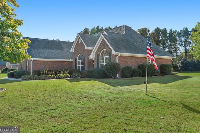 traditional-style home featuring brick siding, a front lawn, and a shingled roof