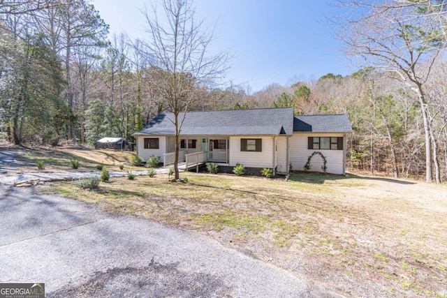 ranch-style house with a porch and a wooded view