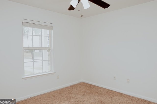 empty room with carpet flooring, a ceiling fan, and baseboards