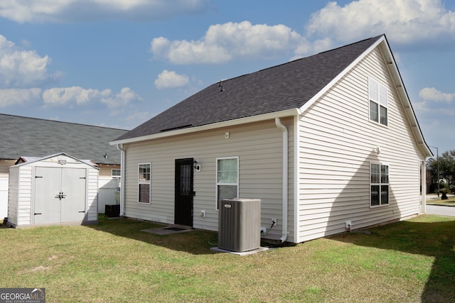 rear view of property with an outbuilding, a lawn, cooling unit, and a storage unit