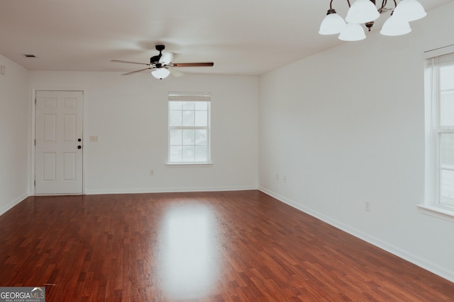 unfurnished room with dark wood finished floors, ceiling fan with notable chandelier, and baseboards
