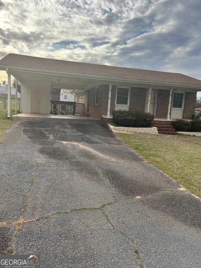 view of front of home with aphalt driveway, a carport, brick siding, and a front lawn