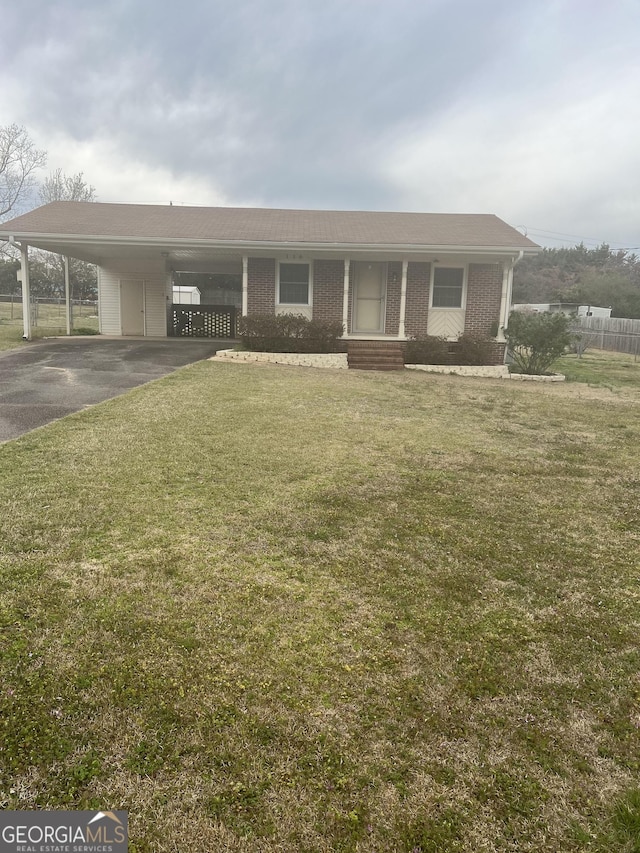 view of front of house with an attached carport, brick siding, a front yard, and aphalt driveway