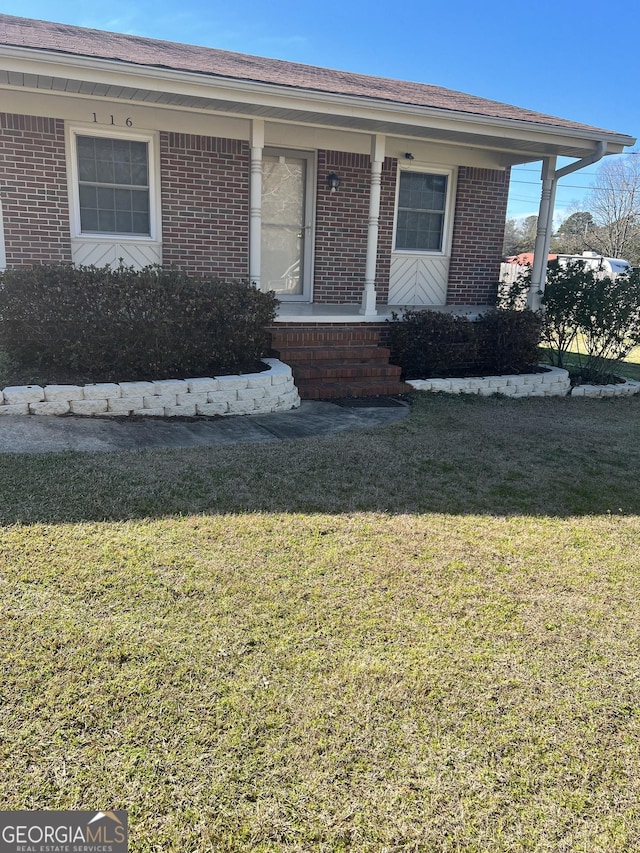 bungalow-style house featuring brick siding, a porch, and a front yard