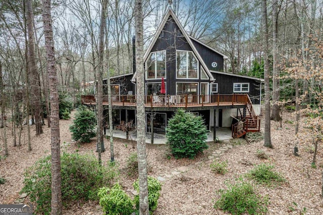 rear view of property featuring stairway, a patio area, and a wooden deck