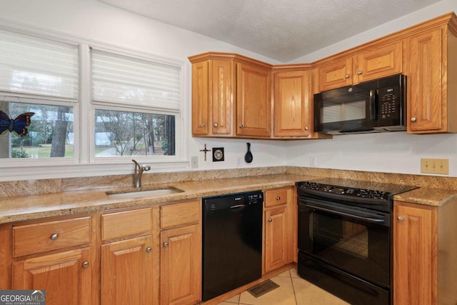 kitchen featuring light tile patterned floors, a textured ceiling, a sink, light stone countertops, and black appliances