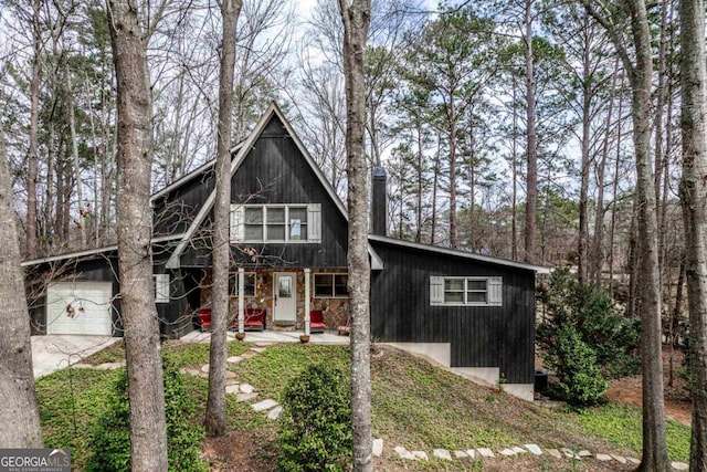 view of front of house featuring a garage, stone siding, and driveway