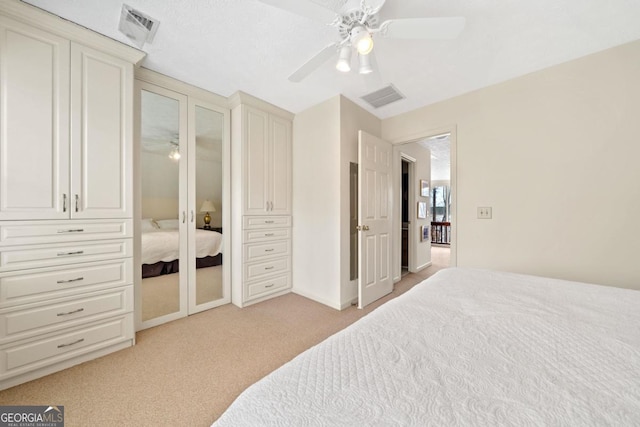 bedroom with light carpet, multiple closets, visible vents, and a ceiling fan